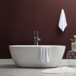 Moderná kúpeľňa s bielou vaňou a hlbokou, sýto vínovou stenou Adventurer od Little Greene.