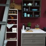 Kuchyňa s bielymi skrinkami, otvorenými policami a sýtou stenou v odtieni Divine Damson od Graham & Brown.