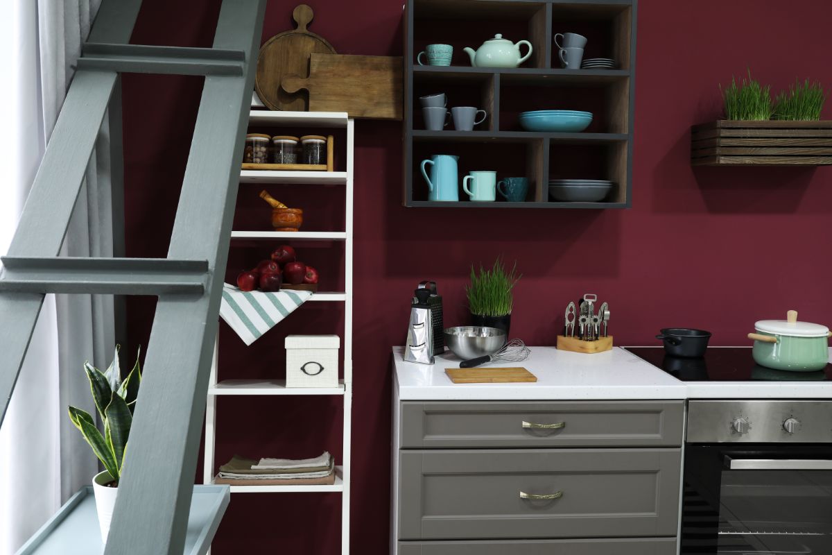 Kuchyňa s bielymi skrinkami, otvorenými policami a sýtou stenou v odtieni Divine Damson od Graham & Brown.