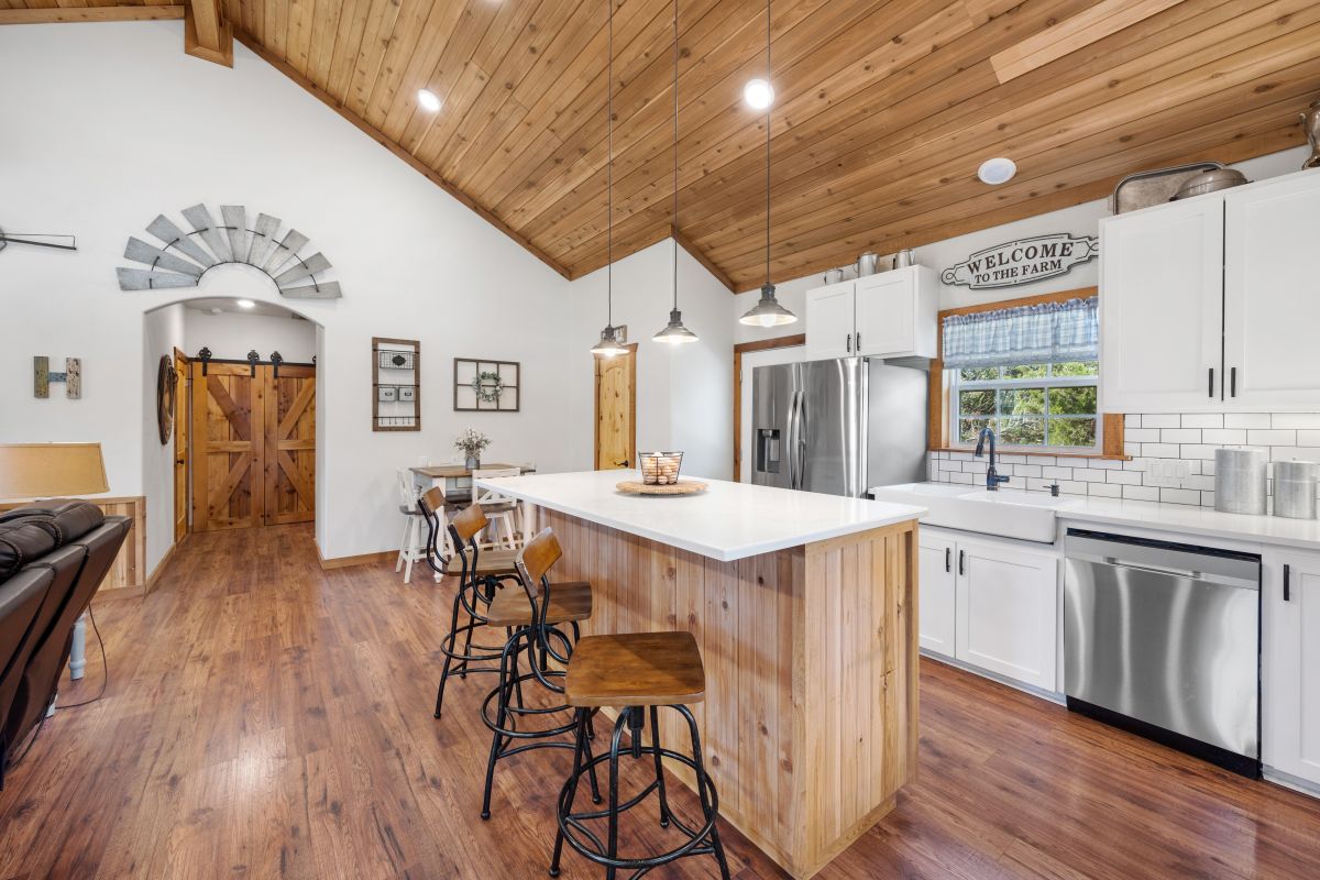 Kuchyňa s bielymi skrinkami, drevenou šikmou stenou a hnedou drevenou podlahou.