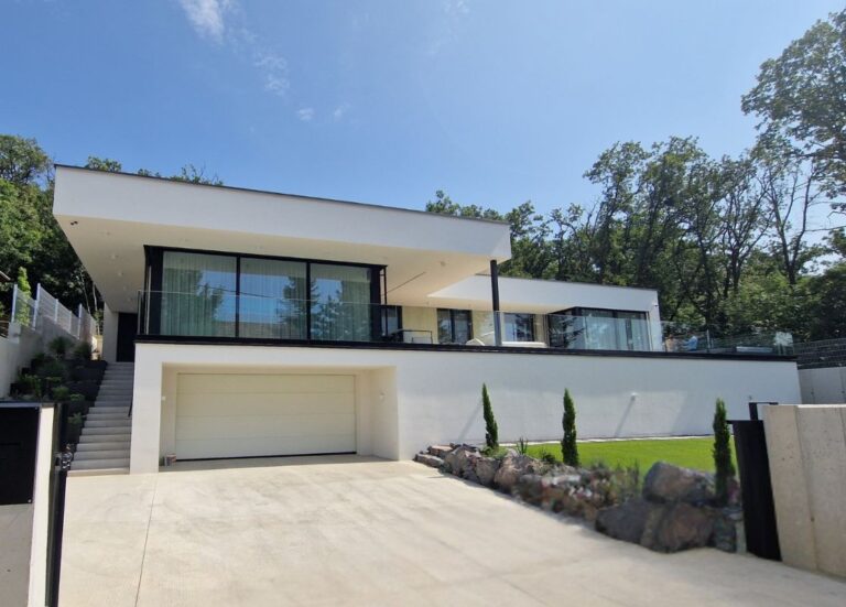 Moderný rodinný dom s rovnou strechou a preskleným zábradlím.