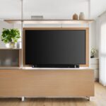 Televízna stena s drevenou skrinkou, integrovanou poličkou a dekoratívnym skleneným panelom.