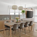 Moderná jedálenská zostava s tmavosivým stolom, stoličkami a bielou závesnou lampou v otvorenom priestore.
