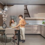 Žena a chlapec pri stole v modernej kuchyni s linkou v svetlohnedom odtieni.