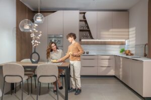 Žena a chlapec pri stole v modernej kuchyni s linkou v svetlohnedom odtieni.
