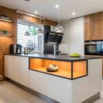 Moderná kuchynská linka s bielymi a drevnými skrinkami a čiernou pracovnou doskou.