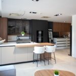 Moderná bielo-čierna kychynská linka so skrinkou s tmavého dreva.