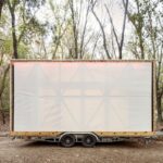 Mobilný dom na prívese s bielou látkovou fasádou.