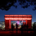 Otvorený a osvetlený mobilný dom na kopci s DJom a publikom.