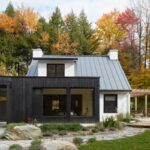 Moderný vidiecky dom s prístavbou s opaľovaného dreva pri lese.