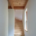 Schody s drevenou nášľapnou plochou, bielymi stenami a dreveným trámovým stropom.