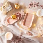 Ružovo-biele keramické misky v tvare cukríkov s vianočnými guľami na svetlej textilnej podložke so svetielkami.