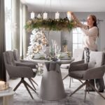 Moderná jedálenská súprava so šedým betónovým stolom, sivými stoličkami a veľkým závesným adventným vencom so sviečkami.