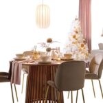 Moderný okrúhly stôl s dreveným rebrovaným podstavcom, zamatovými stoličkami a slávnostným ružovým prestieraním.