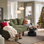 Priestor obývačky s veľkou tmavozelenou rohovou sedačkou, svetlým kobercom a tradičným vianočným stromčekom s farebnými ozdobami.