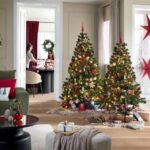 Dva osvetlené vianočné stromčeky s červeno-zlatými ozdobami v priestrannej obývacej izbe s drevenou podlahou.