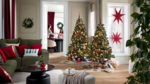 Dva osvetlené vianočné stromčeky s červeno-zlatými ozdobami v priestrannej obývacej izbe s drevenou podlahou.