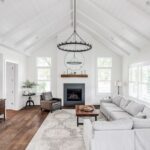 Priestranná obývačka s vysokým bielym dreveným stropom, krbom s čiernym obložením a veľkou sivou rohovou sedačkou.