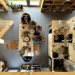 Pohľad zhora na rodinu pri drevenom jedálenskom stole a kuchynskej linke na šedej podlahe.