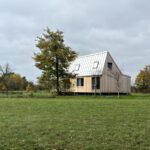 Moderný drevený dom so svetlou šikmou plechovou strechou a strešnými oknami.