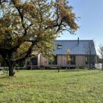 Fasáda moderného dreveného domu s viacerými veľkými oknami na prízemí.