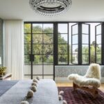 Luxusná spálňa s kvetinovou tapetou, krištáľovým lustrom a veľkými kovovými francúzskymi oknami.