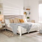 Útulná moderná spálňa s posteľou s čalúneným čelom, kreslom a úložnými nikami.