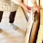 Stará žena sa dotýka starých obrazov na zemi.