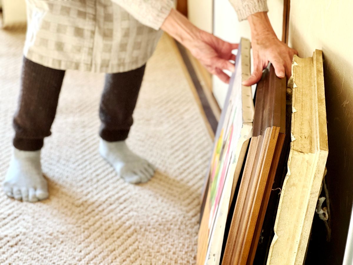 Stará žena sa dotýka starých obrazov na zemi.