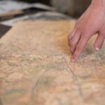 Človek ukazuje prstom miesto na starej mape.