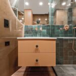 Kúpeľňa so skrinkou v terakotovej farbe a zelenými obkladačkami.