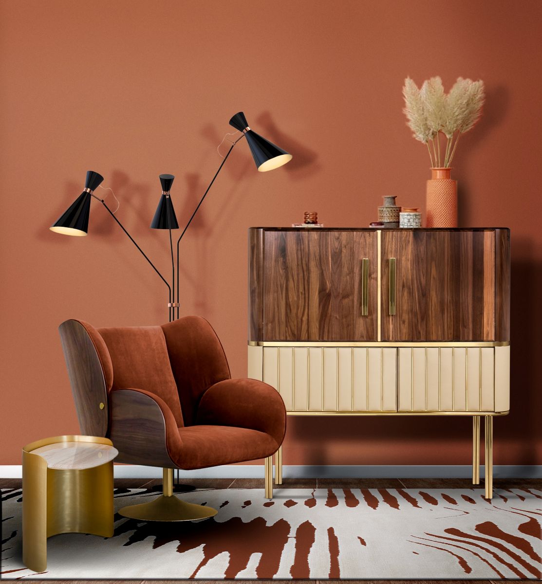 Mäkké kreslo v odtieni terakoty vedľa drevenej retro skrinky a lampy.
