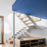 Svetlé drevené schodisko s transparentným skleneným zábradlím a výrazným kobaltovo modrým podhľadom.