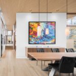 Moderná jedáleň s veľkým dreveným stolom, dizajnovými lampami a oknami po celej výške s výhľadom na les.