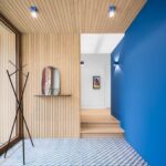 Vstupná hala s dreveným lamelovým obkladom, kobaltovo modrou stenou a modro-bielymi geometrickými dlaždicami.