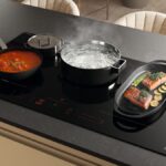 Široká varná doska s množstvom nádob s pripravujúcim sa jedlom.