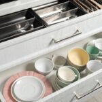 Zásuvky s hrnčekmi, šálkami a tanierikmi.