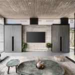 Moderná spoločenská miestnosť s betónovými stenami a stropom, koženým kreslom a kovovými odkladacími stolíkmi v zelenej farbe.