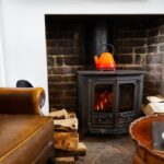 Detail na starú kovovú piecku pri koženom kresle a historickom stolčeku.