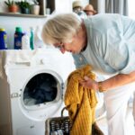 Stará žena pri nakladaní práčky.