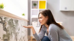 Žena sa díva na stenu s plesňami.