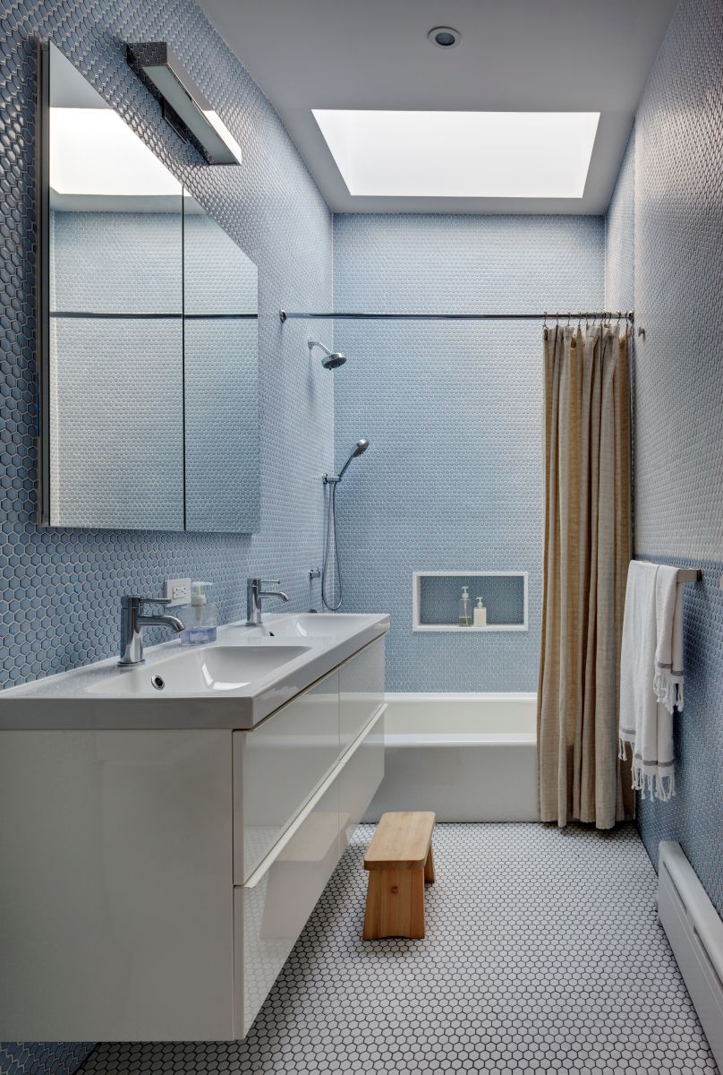Druhá kúpeľňa na poschodí má ako jedna z mála miestností steny farebné, nie biele. Zvolený tu bol jemný mozaikový vzor v svetlomodrom odtieni.