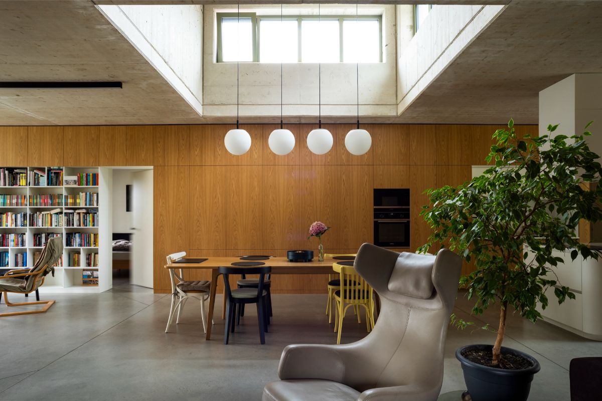 Všadeprítomné svetlé drevo vizuálne zohrieva chladne pôsobiaci betón na strope.