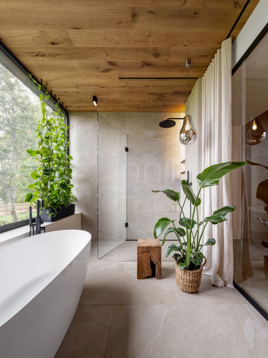 Kúpeľňa s dreveným stropom, obkladom v prírodných farbách a rastlinami pôsobí ako wellness kútik na dobrý relax.