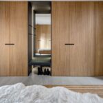 Moderná predsieň so vstavanými drevenými skriňami, sedením v nike a bielou huňatou predložkou.