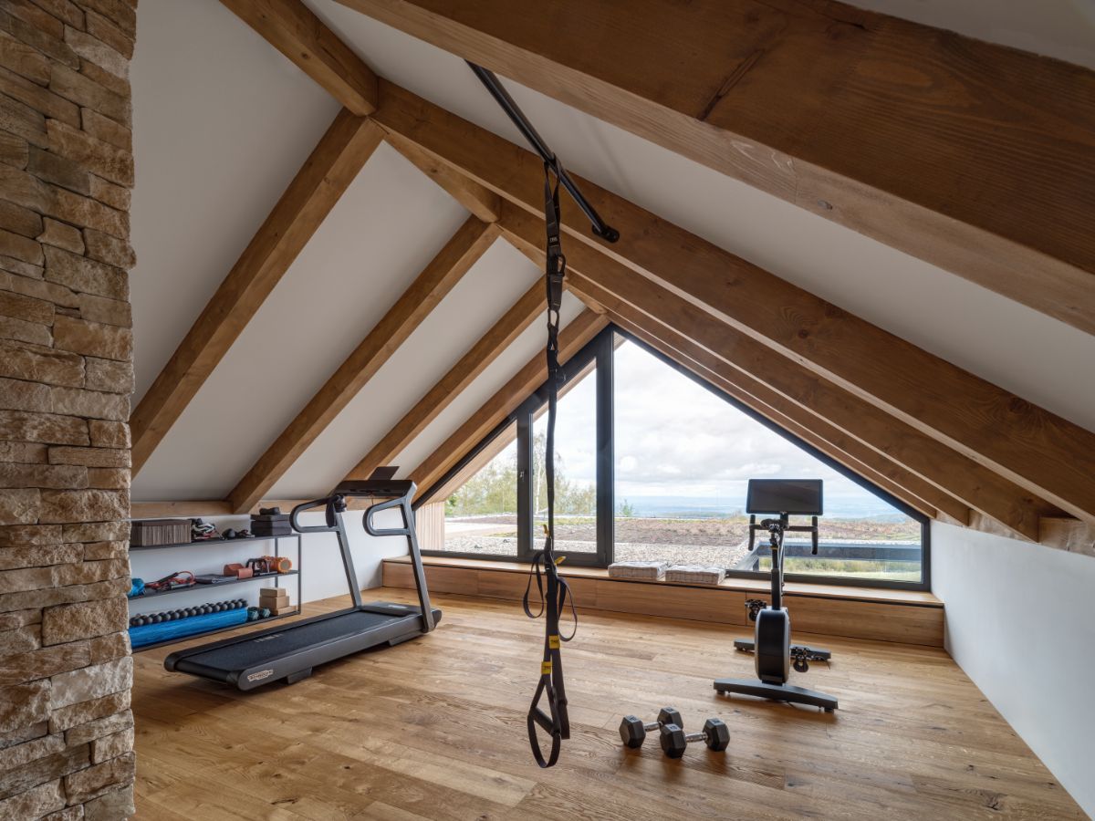 V podkroví oproti pracovni nájdete domácu posilňovňu.  Presklený štít funguje aj ako východ na zelenú strechu nižšej hmoty domu.