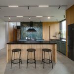 Kuchyňa s drevenými obkladmi, modernou linkou s ostrovčekom s barovým sedením a výrazným tmavozeleným obkladom.