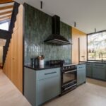 Kuchynská časť s tmavozelenou linkou, čiernym sporákom, digestorom a vertikálnym zeleným obkladom.