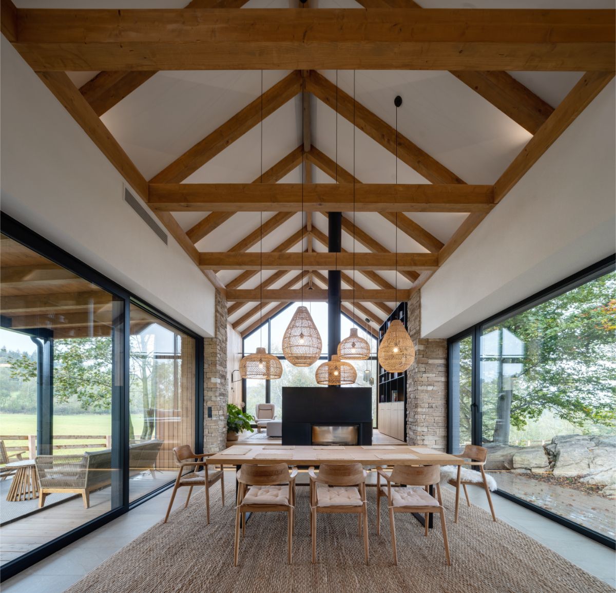 Otvorená denná zóna s jedálenským stolom pri dvoch presklených stenách a kozube.