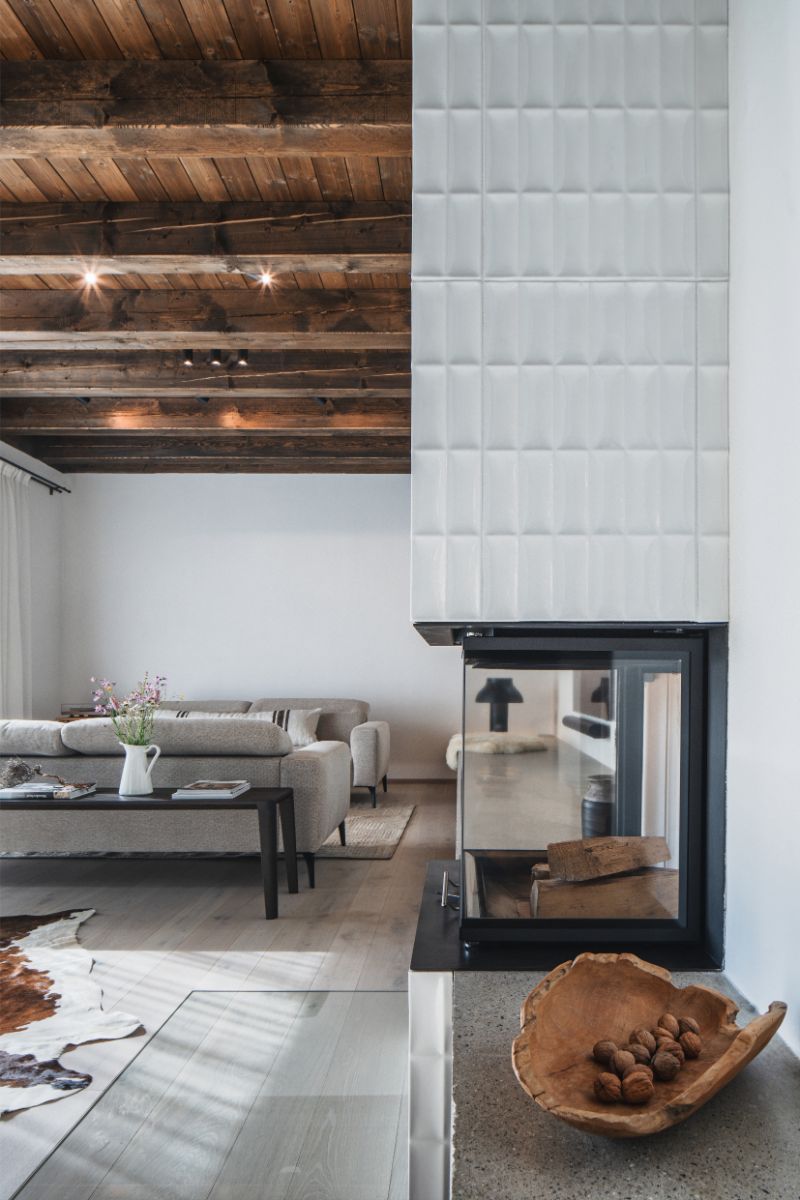 Okolo kachľovej peci sa zhromaždila denná relaxačná zóna s kreslom s výhľadom na oheň i lavicou pri okne.
